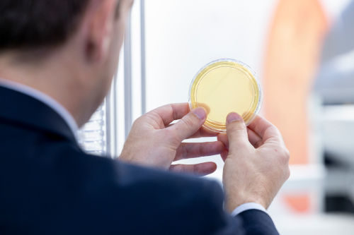 Image: Man looking at a component made of yellow glass; Copyright: Messe Düsseldorf